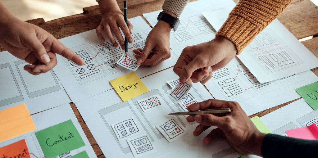 Close up ux developer and ui designer brainstorming about mobile app interface wireframe design on table with customer breif and color code at modern office.Creative digital development agency..
